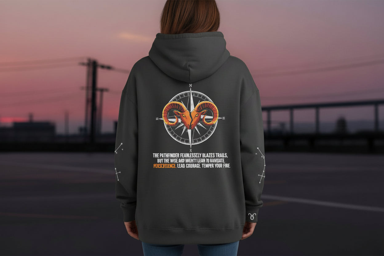 Person wearing a hoodie with a design on the back, under it "The Pathfinder fearlessly blazes trails, but the Wildcard must learn to navigate with patience. Lead with courage, temper your fire."standing outdoors with a sunset or sunrise in the background.